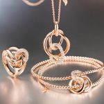 Capolavoro Cielo Ring, Armband und Halskette mit Anhaenger in Rosegold mit Diamanten auf grauem Hintergrund