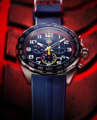 TAG Heuer Formula 1 Chronograph in Stahl mit blauer Luenette, Zifferblatt und Kautschukband auf Reifen liegend