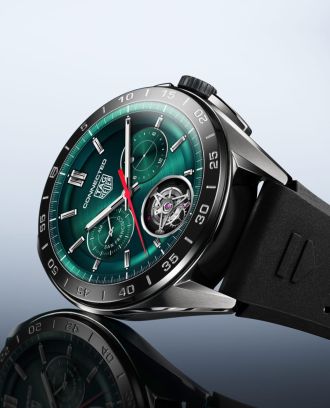 TAG Heuer Connected Smartwatch in Stahl mit Display im Zifferblattdesign und schwarzem Kautschukband seitlich auf grauem Untergrund liegend