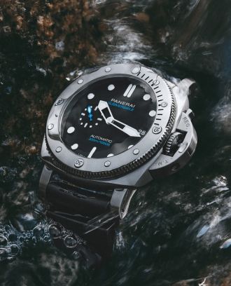 Panerai Submersible Taucheruhr in TItan mit schwarzem Zifferblatt und Kautschukband im Wasser liegend