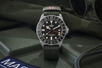 TUDOR Pelagos FXD GMT in Titan mit schwarzer Luenette, Zifferblatt und militarygruenem Textilarmband vor Lifestylehintergrund