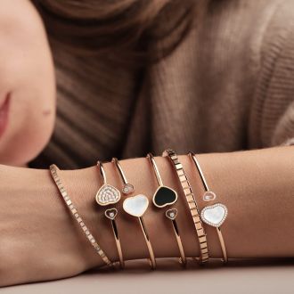 Weibliches Model mit mehreren Happy Hearts und Ice Cube Armreifen von Chopard am Arm