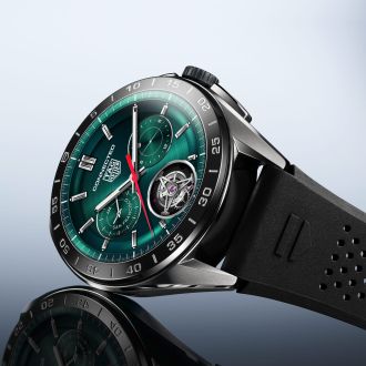 TAG Heuer Connected Smartwatch in Stahl mit Display im Zifferblattdesign und schwarzem Kautschukarmband seitlich auf grauem Untergrund liegend