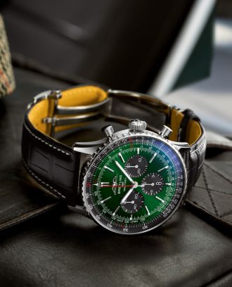 Breitling Navitimer Chronograph in Stahl mit gruen-schwarzem Panda-Zifferblatt mit schwarzem Lederarmband seitlich auf schwarzem Lederuntergrund liegend