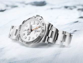 Rolex Explorer Uhr in Edelstahl mit weissem Zifferblatt auf Schneeuntergrund liegend mit Gebirge im Hintergrund