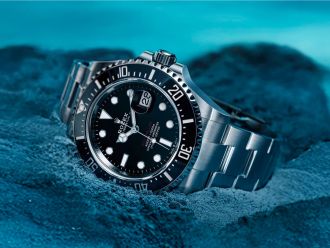 Rolex Sea-Dweller in Edelstahl mit schwarzem Zifferblatt und schwarzer Luenette am Meeresuntergrund liegend