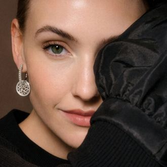 Ohrhänger aus Weißgold mit Diamanten in rundem Design, getragen am Ohr, elegante Detailaufnahme.