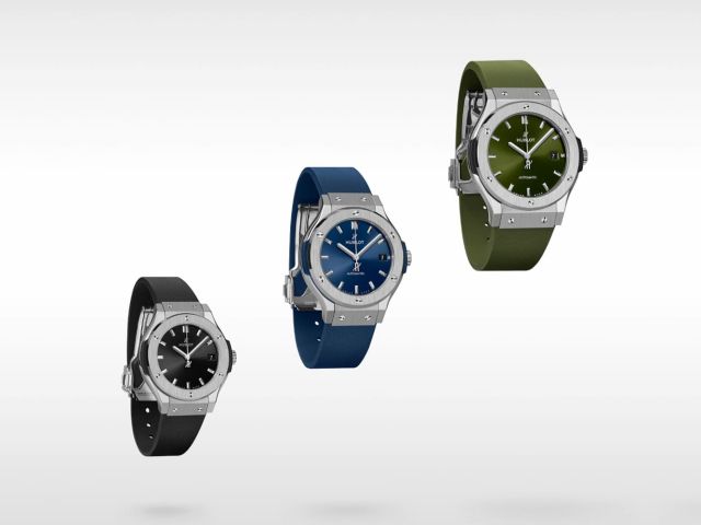 Drei schlichte Hublot Classic Fusion Uhren mit Edelstahlgehäuse und farbigen Armbändern in Schwarz, Blau und Grün vor weißem Hintergrund.