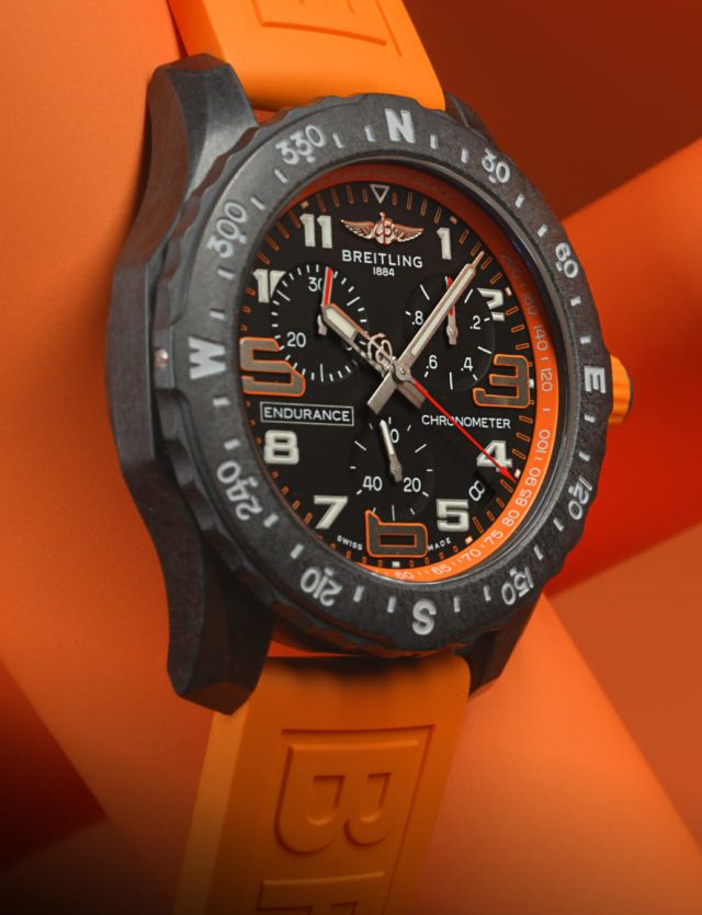 Breitling Endurance Pro Uhr mit Breitlight Gehaeuse, schwarzem Zifferblatt und orangefarbenem Kautschukband auf orangefarbenem Hintergrund