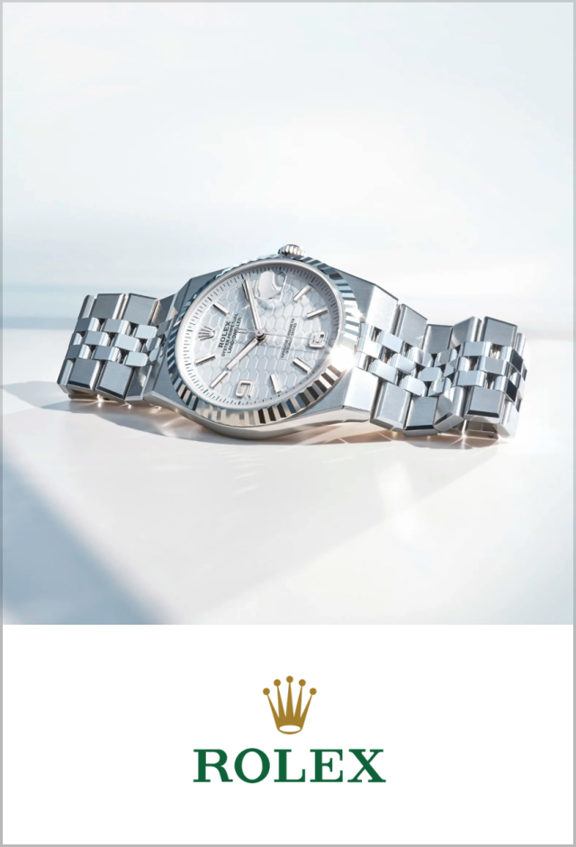 Detailaufnahme der Rolex Land-Dweller Armbanduhr aus Edelstahl mit Jubilee-Armband und strukturiertem silberfarbenem Zifferblatt, darunter Rolex Markenlogo auf weißem Hintergrund.