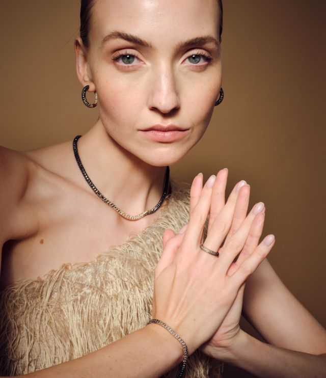 Frau mit Schmuck aus der Radiant-Kollektion des Atelier Mühlbacher – edler Look mit Diamant-Creolen, Halskette, Armband und Ring in warmem Licht.