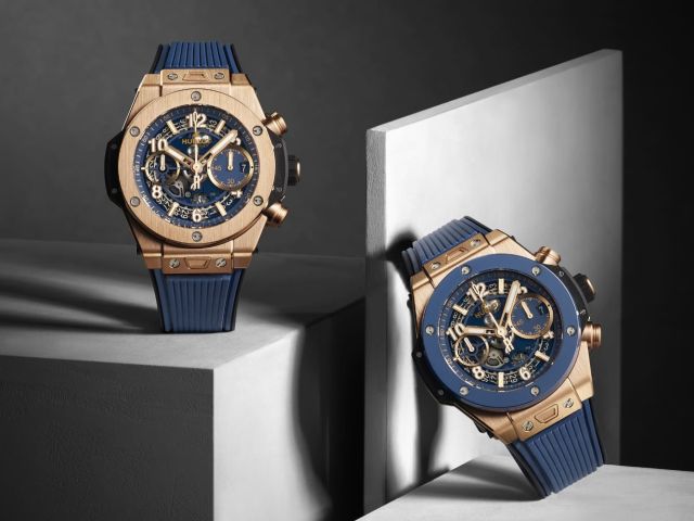Zwei luxuriöse Hublot Big Bang Uhren aus Roségold mit blauem Zifferblatt und blauem Kautschukarmband auf geometrischen Podesten inszeniert.