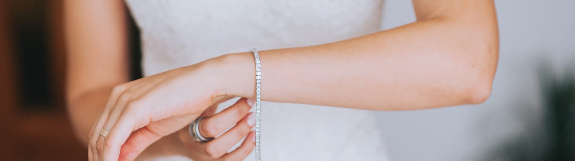 Frau im Brautkleid legt sich ihr Diamantarmband an