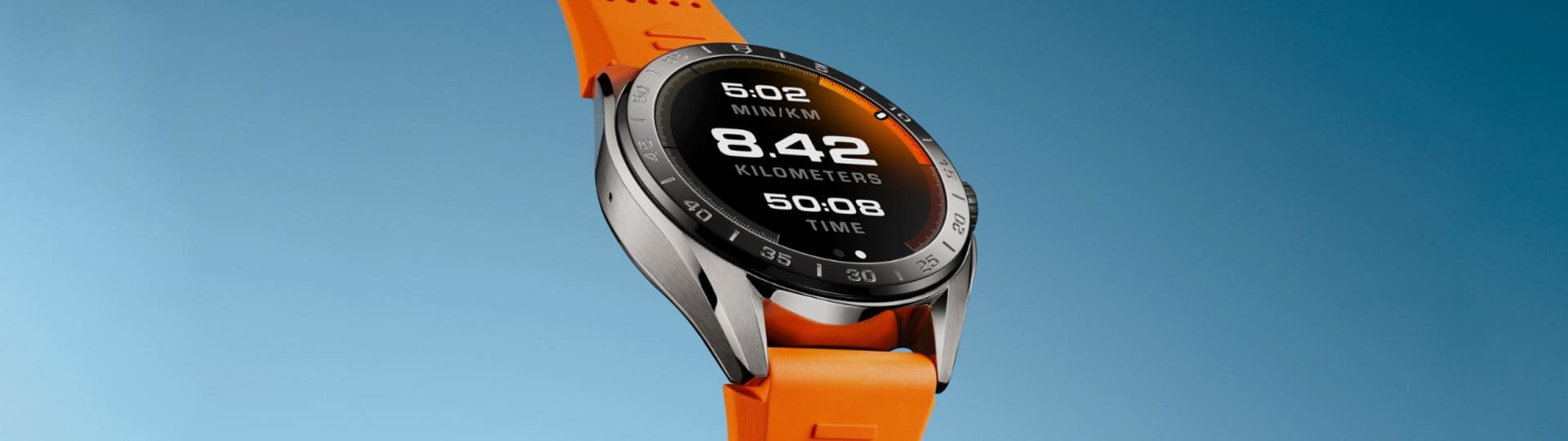 TAG Heuer Connected Smartwatch in Stahl mit Displayzifferblatt und orangefarbenem Kautschukband vor blauem Hintergrund