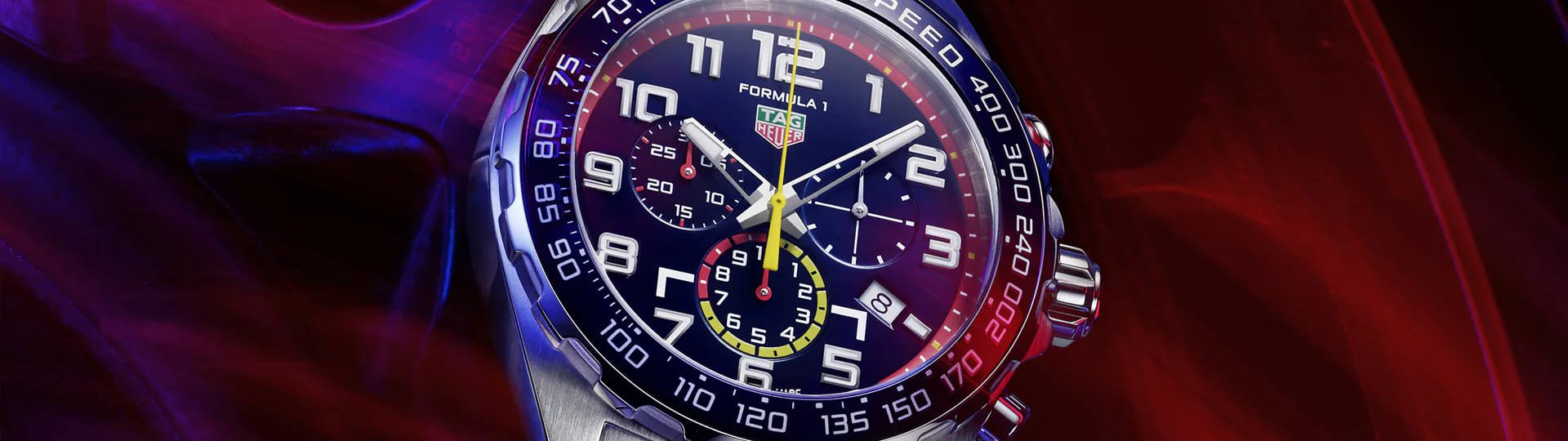 Tag Heuer Formula 1 Chronograph in Stahl mit blauer Luenette und blauem Zifferblatt vor blau-rotem Hintergrund