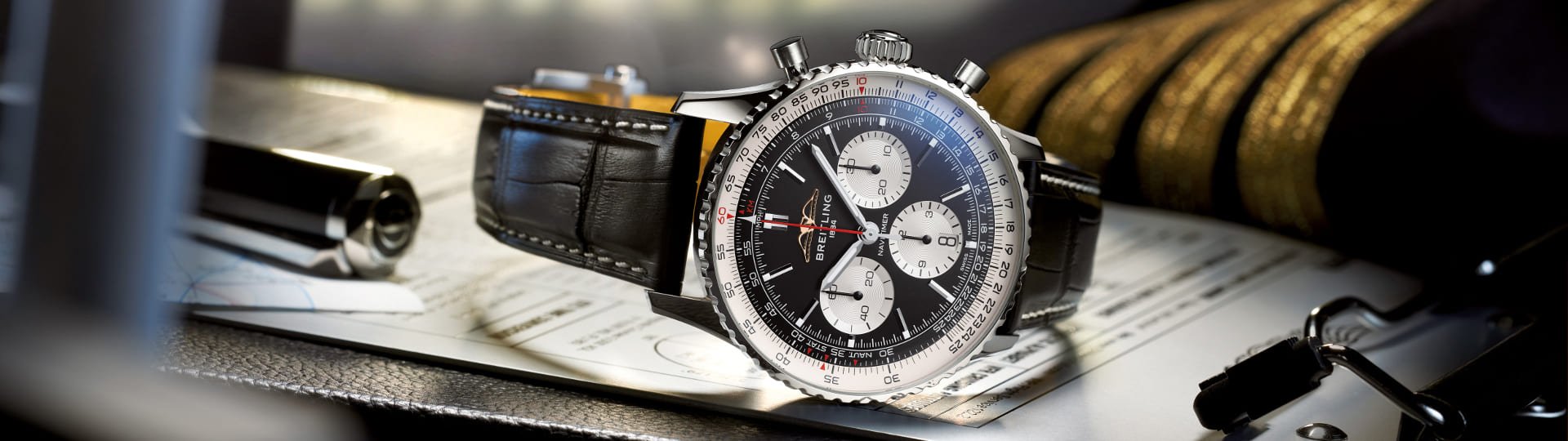 Breitling Navitimer Chronograph in Stahl mit schwarzem Zifferblatt und schwarzem Lederarmband seitlich auf Flugunterlagen liegend