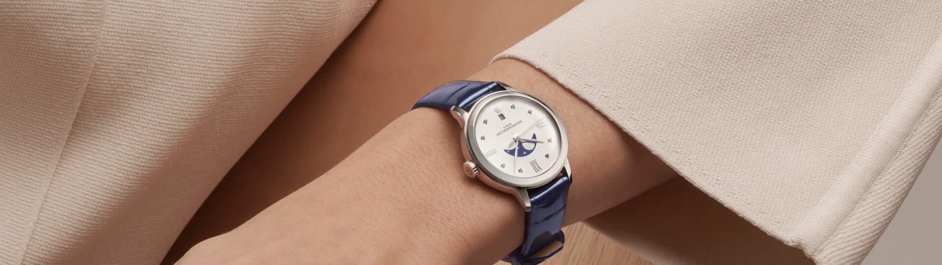 Classima Uhr von Baume & Mercier in Stahl mit weissem Perlmuttzifferblatt mit Mondphase und blauem Lederarmband an einem Damenhandgelenk getragen