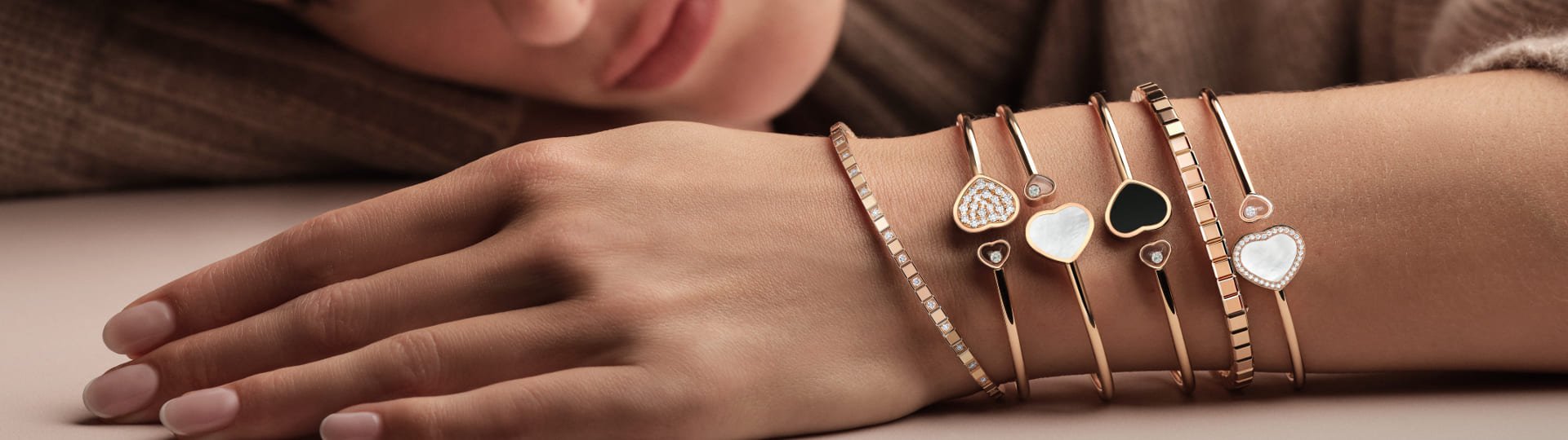 Weibliches Model mit 4 Happ Hearts Armreifen und 2 Ice Cube Armbaender jeweils in Rosegold im Layering Look an einem Arm