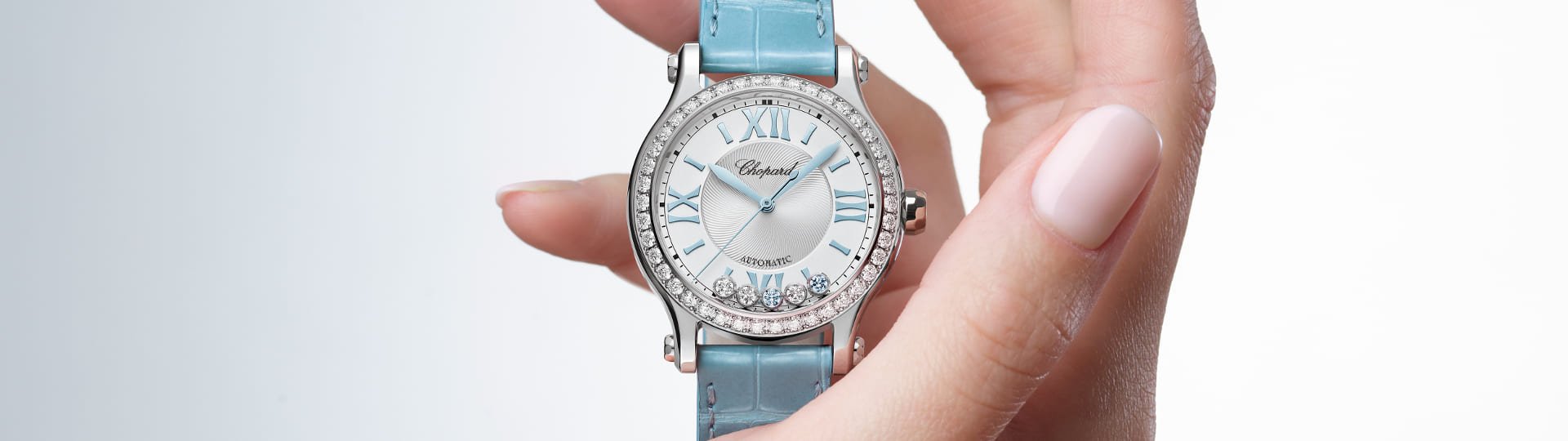 Chopard Happy Sport Damenuhr mit Gehaeuse in Stahl mit Diamantluenette, silbernem Zifferblatt mit 5 beweglichen Diamanten und hellblauem Lederarmband stehend auf einer Hand