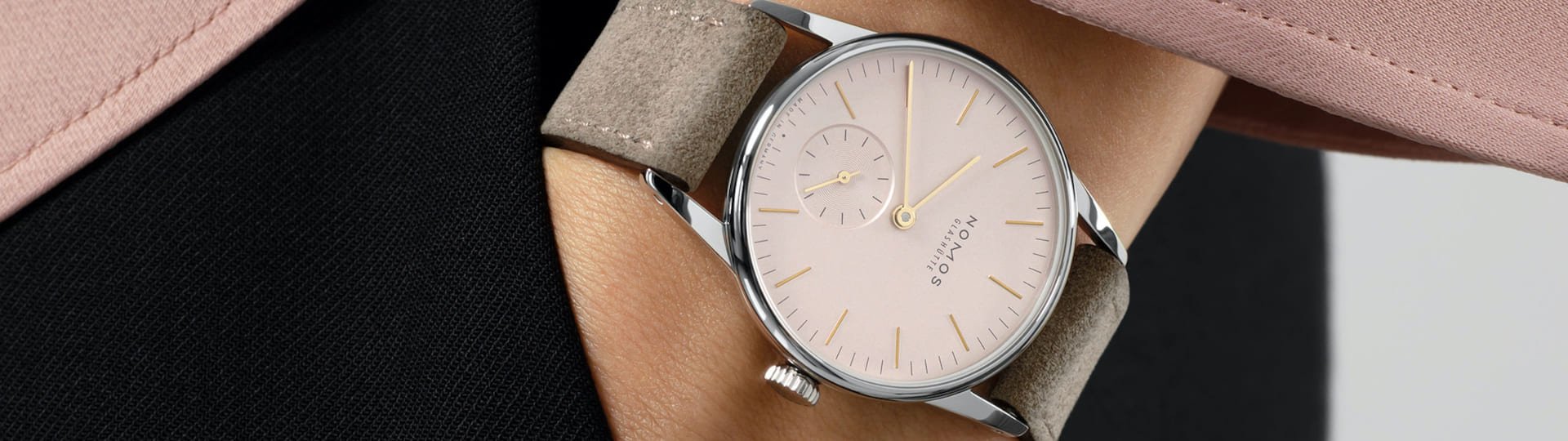 Weibliches Model mit NOMOS Glashuette Uhr in Stahl mit rosefarbenem Zifferblatt und Lederarmband am Handgelenk