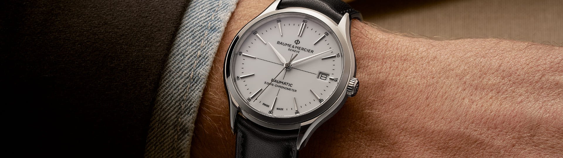 Herrenhandgelenk mit einer Baume & Mercier Clifton Baumatic Uhr in Stahlmit weissem Zifferblatt und Lederarmband