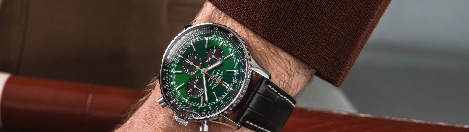 Breitling Navitimer Chronograph in Stahl mit gruenem Zifferblatt und schwarzem Lederarmband an einem Herrenhandgelenk