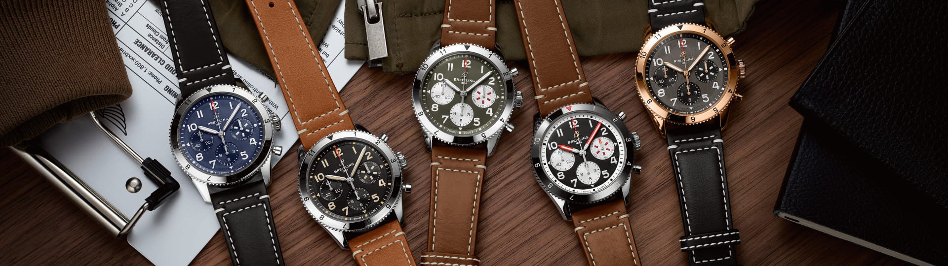 Fünf Classic AVI Chronographen von Breitling auf Holzhintergrund liegend