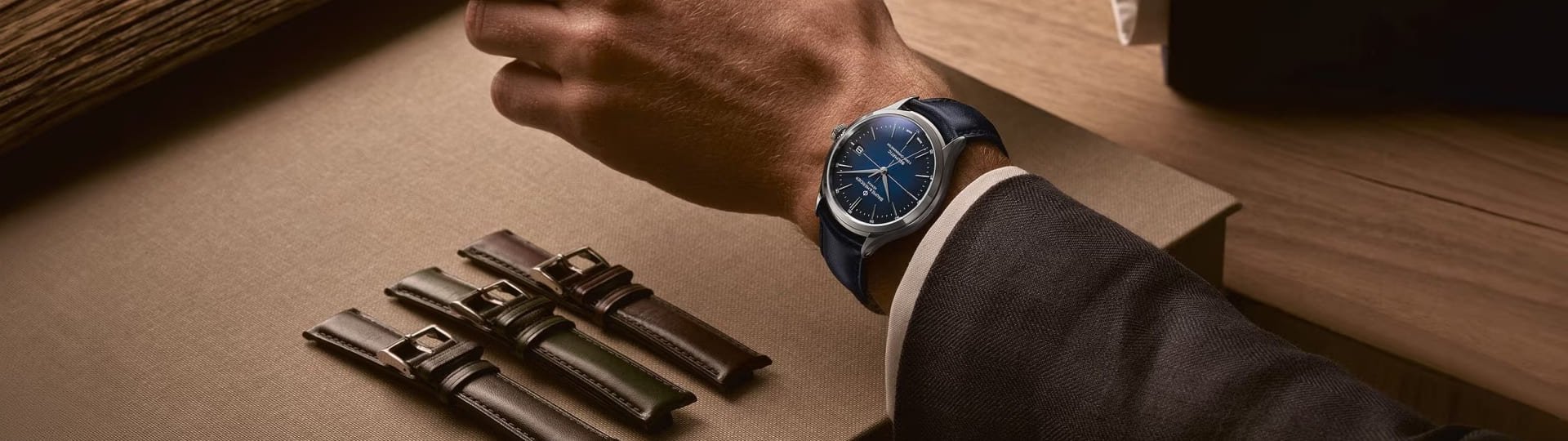 Clifton Baumatic Herrenuhr in Stahl mit blauem Zifferblatt und Lederarmband getragen an einem Herrenhandgelenk, drei Lederarmbaender zu Austauschen liegen daneben