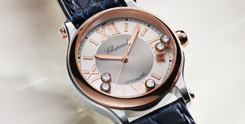 Chopard Happy Sport Damenuhr mit Gehaeuse in Stahl, Krone und Luenette in Rosegold, silbernem Zifferblatt mit roemischen Ziffern und 5 beweglichen Diamanten vor beigefarbenem Hintergrund