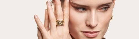 Weibliches Model mit gelbgoldenen Curriculum Vitae Ring mit quadratischen Diamanten am Mittelfinger getragen