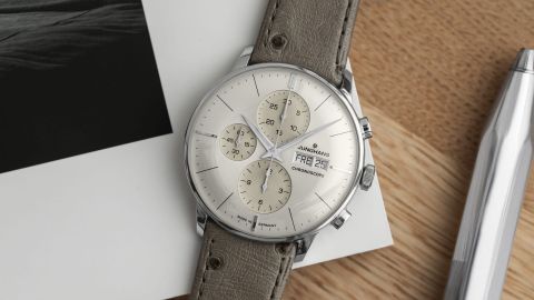Junghans Meister Chronograph in Stahl mit silbergrauem Zifferblatt und taupefarbenem Lederarmband auf Schreibtisch liegend Junghans Meister Chronograph in Stahl mit silbergrauem Zifferblatt und taupefarbenem Lederarmband auf Schreibtisch liegend