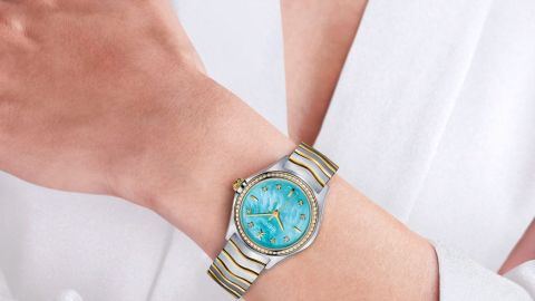 Ebel Wave Damenuhr mit Stahlgehaeuse, Gelbgoldluenette mit Diamanten, tuekisfarbenem Perlmuttzifferblatt und Bicolorarmband am Handgelenk getragen Ebel Wave Damenuhr mit Stahlgehaeuse, Gelbgoldluenette mit Diamanten, tuekisfarbenem Perlmuttzifferblatt und Bicolorarmband am Handgelenk getragen