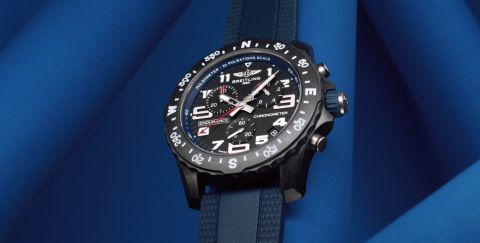 Breitling Professional Uhr mit schwarzem Breitlight Gehaeuse, schwarzem Zifferblatt und dunkelblauem Kautschukarmband vor blauem Hintergrund