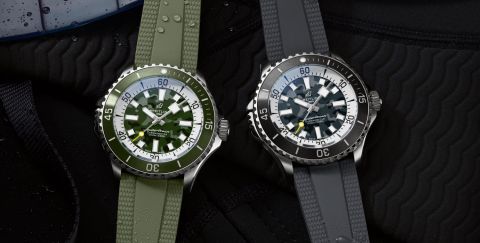 Zwei Breitling Superocean Diver Uhren in Stahl, mit khakigruenem und schwarzen Zifferblätter und entsprechenden Kautschukarmbaendern auf dunklem Hintergrund