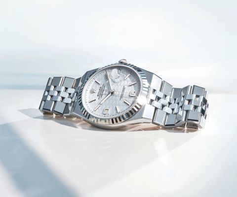 Rolex Land-Dweller Armbanduhr aus Edelstahl mit Jubilee-Armband und silberfarbenem Zifferblatt, liegend auf hellem, minimalistischem Untergrund.