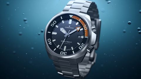 Junghans Aquaris Diver Taucheruhr aus Edelstahl mit dunkelgrauem Zifferblatt und Datumsanzeige vor blauem Unterwasser-Hintergrund. Junghans Aquaris Diver Taucheruhr aus Edelstahl mit dunkelgrauem Zifferblatt und Datumsanzeige vor blauem Unterwasser-Hintergrund.
