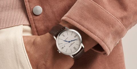 Baume Mercier Classima Uhr in Stahl mit weissem Zifferblatt und braunem Lederarmband an einem Herrenhandgelenk getragen