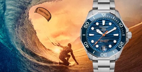 Tag Heuer Aquaracer Uhr in Stahl mit blauer Luenette und blauem Zifferblatt vor Meereshintergrund mit Kitesurfer